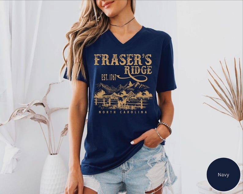 A woman wearing a navy blue t-shirt with a graphic design of a mountain range and the text "Fraser's Ridge" printed on it.