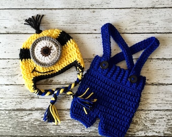 May include: A crocheted Minion hat with a yellow and black design and a large blue eye. A blue crocheted overall with yellow straps.