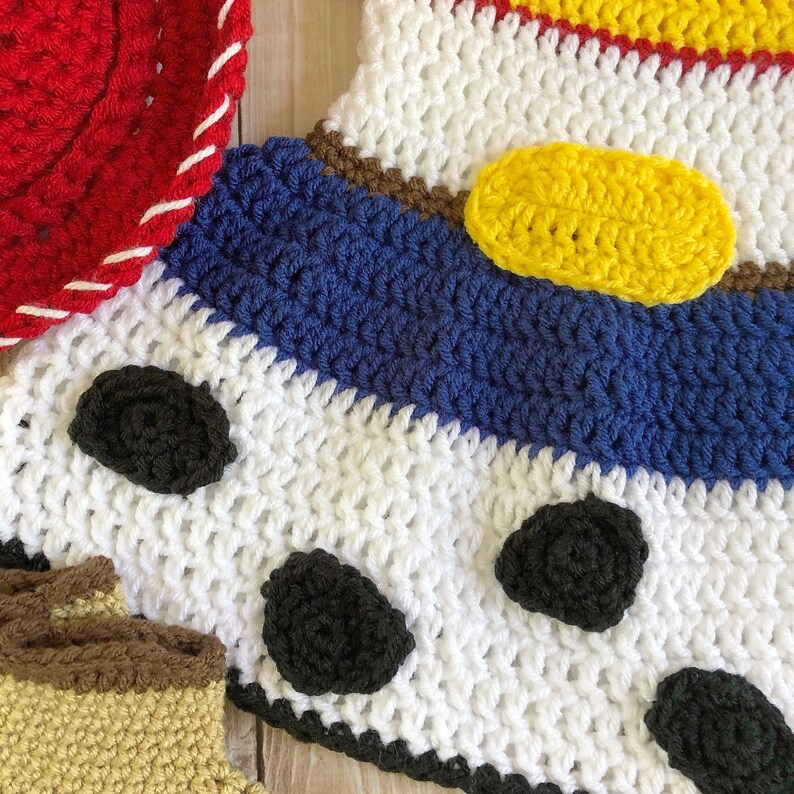 以下が含まれることがあります： 白、青、黄、赤、茶色のストライプ模様のクロシェ編みのベビー服。黒い水玉模様と黄色の楕円形があります。