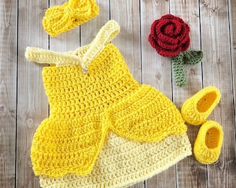 May include: A yellow crocheted dress with a matching headband, a red crocheted rose, and a pair of yellow crocheted shoes. This is a handmade baby outfit inspired by the Disney character Belle.