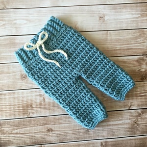 May include: Blue crocheted baby trousers with a white drawstring.