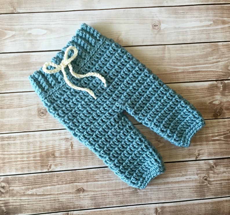 May include: Blue crocheted baby trousers with a white drawstring.