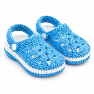 Peut inclure: Une paire de sabots en crochet bleu vif avec une bande blanche sur la semelle intermédiaire, un design supérieur perforé et une bride de talon pivotante fixée par des boutons circulaires blancs. L'intérieur est doublé de fil blanc texturé.
