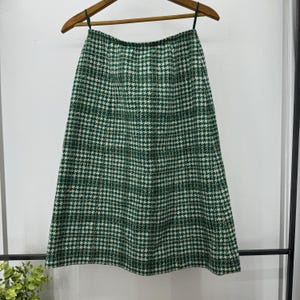 Op de afbeelding: Een groene en witte ruitrok met een hoge taille en een A-lijn silhouet.