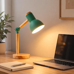 Peut inclure: Lampe de bureau verte et en bois avec une base ronde et un bras réglable. La lampe a un abat-jour vert et un bras et une base en bois. Un ordinateur portable et un bloc-notes sont sur le bureau.
