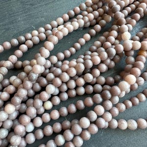 Peut inclure: Gros plan sur plusieurs brins de perles rondes de couleur mauve. Les perles ont une finition mate et sont enfilées ensemble. Les perles sont de taille et de forme uniformes, et la couleur est uniforme. Idéal pour la création de bijoux.