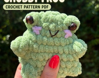 May include: A light green crochet frog plushie with dark brown bead eyes and embroidered pink cheeks. The text CHUBBY FROG CROCHET PATTERN PDF is displayed at the top. The frog has a rounded body, small arms, and a stitched mouth.