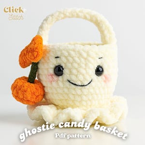 Op de afbeelding: Een crèmekleurige, gehaakte ghostie snoepmand met een lachend gezicht, zwarte ogen en roze wangen. Een oranje pompoen met een groene stengel is aan de zijkant bevestigd. De tekst "ghostie candy basket" en "Pdf pattern" zijn zichtbaar.