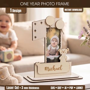 Può includere: Una cornice in legno a forma di numero uno, con una foto di un bambino. La cornice presenta ritagli a forma di stella, dettagli di palloncini e un orsetto. Il nome "Michael" è inciso sulla base. Il testo "ONE YEAR PHOTO FRAME" e "INSTANT DOWNLOAD" sono visibili.