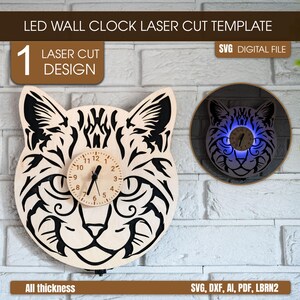 May include: A wooden cat-shaped LED wall clock laser cut design. The clock has a round clock face with black hands and numbers. The image also shows a second illuminated clock. The text "LED WALL CLOCK LASER CUT TEMPLATE" is at the top.
