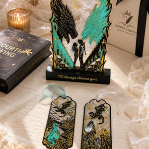 May include: A decorative acrylic display featuring two dragon heads, one black and one teal, flanking a couple, with the text "I'll always choose you." on the base. Two matching bookmarks with dragon and character illustrations are placed in front.