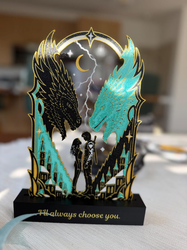 Dragon book stand with two matching Fourth Wing inspired bookmarks displayed on a reading table beside a fantasy book.
