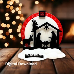May include: A black and white Christmas advent calendar with a nativity scene silhouette. The calendar features a red and white dial with numbers, an angel, a donkey, and the text "A Child Is Born". The base is white and cloud-shaped.