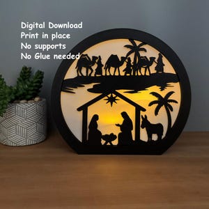 May include: A black, circular, layered Christmas decoration with a nativity scene silhouette. The design includes a stable, palm trees, camels, and figures. The text "Digital Download, Print in place, No supports, No Glue needed" is visible.
