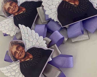 May include: Three decorative angel-themed hair bows. Each bow features a photo of a woman with glasses, a black top, and glittery angel wings. The bows are made with lavender, silver, and gray ribbons.