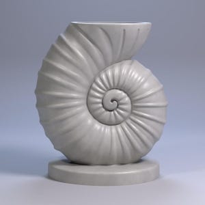 Pode incluir: Um vaso em forma de concha, cinza claro. O vaso tem um design em espiral, com uma base arredondada. A abertura está no topo, e o design geral é suave e elegante. É um objeto decorativo.