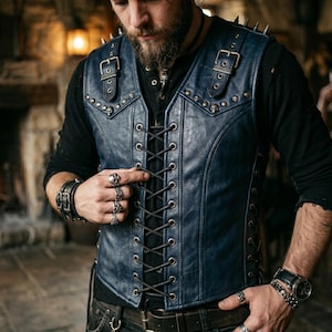 May include: A navy blue leather vest with a lace-up front and skull accents. The vest features silver buckles, metal spikes on the shoulders, and is worn over a black long-sleeve shirt. The vest is a part of a biker or gothic style.