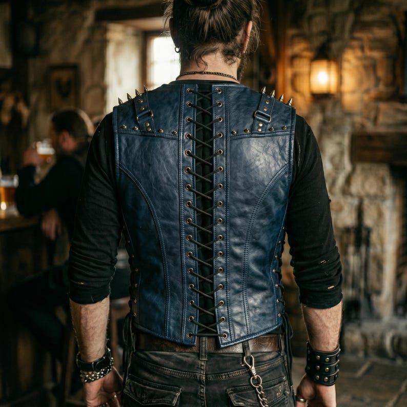 May include: A blue leather vest with a lace-up back and studded accents. The vest has a V-neck and is worn over a black long-sleeved shirt. The vest is part of a gothic or biker-inspired fashion ensemble.