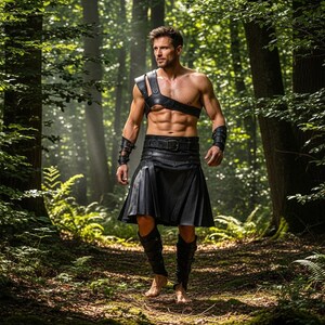 Könnte beinhalten: Ein schwarzer Lederkilt, Schultergurt, Armmanschetten und kniehohe Stiefel werden in einer Waldumgebung getragen. Der Kilt ist plissiert und mit einem Gürtel befestigt. Der Schultergurt und die Armmanschetten sind ebenfalls aus schwarzem Leder.