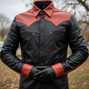 Peut inclure: Une chemise en cuir noir avec des d&eacute;tails rouges sur le col, les &eacute;paules et les poignets. La chemise a une fermeture boutonn&eacute;e, deux poches de poitrine et un logo en bas &agrave; droite. Les manches sont longues, et la personne porte des gants noirs.