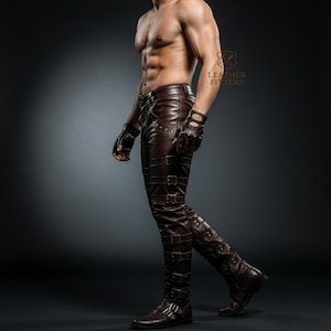 May include: Brown leather pants with multiple buckle straps and matching boots. The pants have a fitted design and are paired with fingerless gloves. The image is set against a dark background.