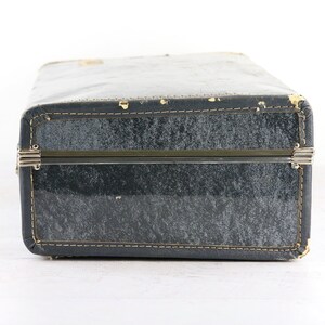 Op de afbeelding: Een vintage blauwe koffer met metalen sluitingen en stiksels rond de randen.