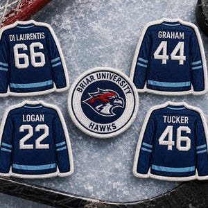 May include: Embroidered patches depicting hockey jerseys with player names and numbers, including "Di Laurentis 66", "Graham 44", "Logan 22", and "Tucker 46". A Briar University Hawks logo patch is also present. The patches are navy blue with light blue accents.