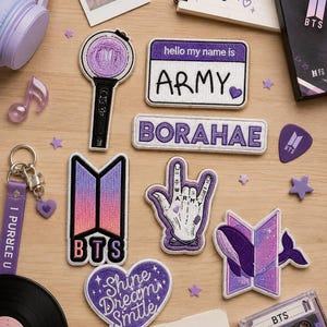 Könnte beinhalten: Eine Sammlung von BTS-Artikeln, darunter Aufnäher, ein Schlüsselanhänger und eine Kassette. Die Aufnäher zeigen das BTS-Logo, das Wort "ARMY" und andere Designs in Lila und Weiß. Ein lila Lichtstab und Kopfhörer sind ebenfalls zu sehen.