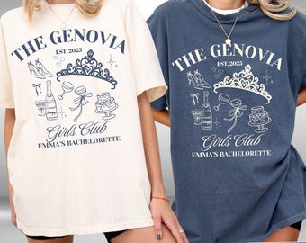 May include: Two oversized t-shirts, one ivory and one denim blue, feature the text "THE GENOVIA EST. 2025 Girls Club EMMA'S BACHELORETTE" in a white and navy blue design. The design includes a crown, high heels, and champagne.