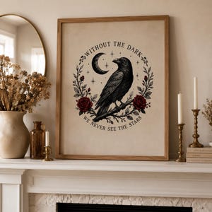May include: A framed wall art print featuring a black raven perched on a branch, surrounded by a wreath of red roses and leaves, a crescent moon, and stars. The text reads, "WITHOUT THE DARK WE NEVER SEE THE STARS" in a circular black font.