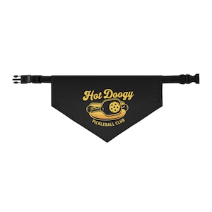 May include: Black dog bandana with the words "Hot Doogy Pickleball Club" in yellow. The design features a pickleball paddle inside a hot dog bun. The bandana has a black adjustable strap with a plastic buckle.