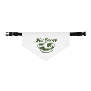 May include: White dog bandana with a black adjustable collar. The bandana features the text "Hot Doogy Pickleball Club" in a green, vintage-style font, along with a pickleball paddle graphic.