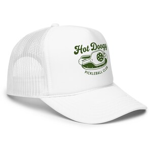 May include: White trucker hat with a curved brim and mesh back. The hat features the text "Hot Doogy Pickleball Club" in green, along with a pickleball paddle graphic.