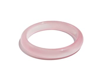 May include: A translucent, light pink bangle bracelet. The smooth, rounded design of the bracelet is visible against a white background. The bangle is a solid, circular band, showcasing a minimalist aesthetic.