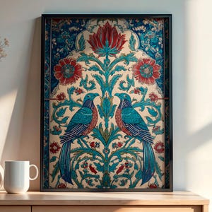 Könnte beinhalten: Gerahmtes Kunstwerk mit zwei türkisblauen Vögeln auf einem floralen Zweig. Das Kunstwerk hat einen cremefarbenen Hintergrund mit roten und türkisfarbenen floralen Elementen. Der Rahmen ist schwarz. Auf einem Holzschrank mit weißen Vasen und einer Tasse.