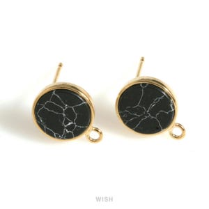 May include: A pair of gold-toned stud earrings. Each earring features a round, black stone with white veining, set within a gold-colored bezel. The earrings have a post and a small loop for attaching to other jewelry components.