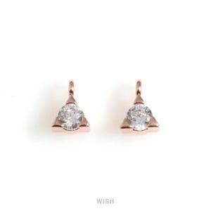 Puede incluir: Dos colgantes triangulares de oro rosa con una gema redonda y transparente en el centro. Cada colgante tiene un pequeño lazo en la parte superior para sujetarlo a la joyería. La palabra "WISH" está impresa en el centro inferior.