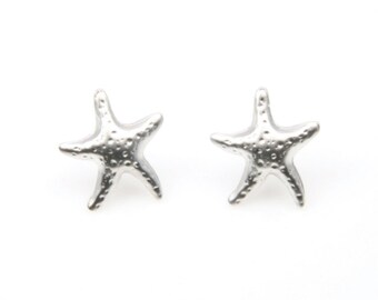 May include: A pair of silver-colored starfish stud earrings. Each earring is a detailed starfish shape with a textured surface. The earrings are displayed on a white background.