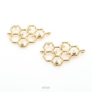 May include: Two gold-colored honeycomb-shaped jewelry findings with small, clear crystals. Each piece has a series of hexagonal shapes connected together, with a loop on each end for attaching to other jewelry components. The background is white.