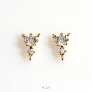 May include: Two gold-colored, decorative earring charms with clear, sparkling gemstones. Each charm features a large, round gemstone at the top, a smaller gemstone below, and a loop at the bottom. The word "WISH" is at the bottom.