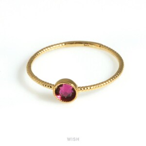 May include: A gold-colored ring with a textured band and a round, deep pink gemstone. The ring is set against a white background. The word "WISH" is printed in white at the bottom of the image.