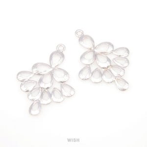 Peut inclure: Deux breloques argentées en forme de goutte d'eau. Chaque breloque est composée de plusieurs cristaux transparents en forme de goutte d'eau disposés en cascade. Les breloques ont une petite boucle en haut pour l'attache. Le mot "WISH" est en bas.