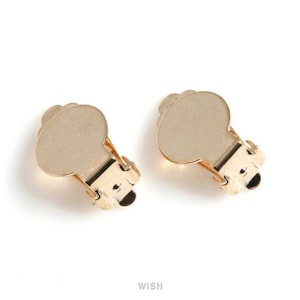 May include: Two gold-colored clip-on earrings. Each earring features a rounded, scalloped top and a hinged clip mechanism. The earrings are displayed against a white background.