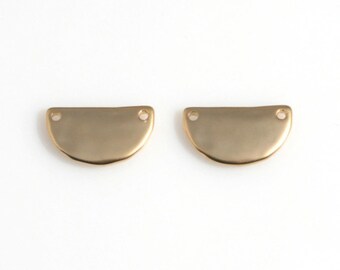 Peut inclure: Deux apprêts de bijoux dorés en forme de demi-cercle. Chaque apprêt comporte deux petits trous près du bord droit. Les apprêts ont une surface légèrement texturée et sont présentés sur fond blanc.