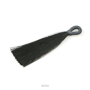 Könnte beinhalten: Eine schwarze Quaste mit einer Schlaufe oben, vor weißem Hintergrund. Die Quaste besteht aus vielen dünnen, schwarzen Strängen. Das Wort "WISH" ist unten im Bild weiß gedruckt.