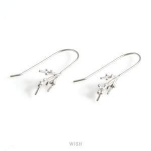 Puede incluir: Un par de ganchos para pendientes de color plateado con un diseño en forma de rama. Cada gancho tiene una parte superior curvada y un pequeño grupo de elementos decorativos. La palabra "WISH" está impresa en la esquina inferior derecha.