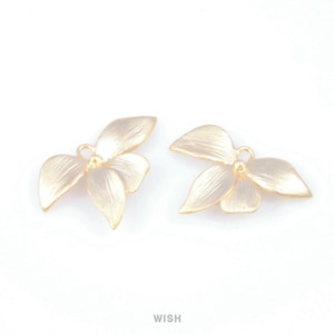 Może przedstawiać: Dwa złote zawieszki w kształcie liści. Każda zawieszka ma trzy liście i małą pętlę u góry do mocowania do biżuterii. Zawieszki mają matowe wykończenie na białym tle.