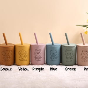 May include: Six colourful silicone cups with straws, each with a different animal design and name. The colours are brown, yellow, purple, blue, green, and pink. These cups are designed for children.