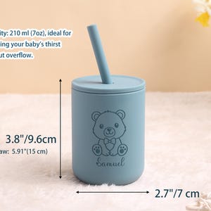 May include: A pale blue baby cup with a lid and straw. The cup has a bear illustration and the name "Samuel". It measures 9.6 cm tall and 7 cm wide. With the straw, it is 15 cm tall. Holds 210 ml. A cute and practical item for babies.