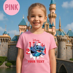 A young girl wearing a pink t-shirt with a Disney character graphic and the text "Disney STILTON" printed on it, standing in front of a castle.